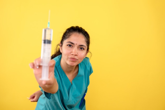 Free photo front view of young female doctor showing syringe on yellow isolated wall