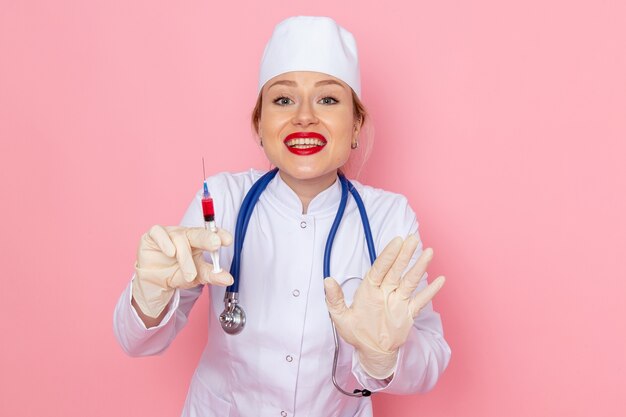 파란색 청진기 주사를 들고 분홍색 공간 의학 의료 병원 여성에 웃 고 흰색 의료 소송에서 전면보기 젊은 여성 의사