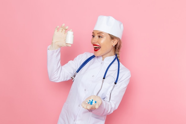 파란색 청진 기 핑크 공간 의학 의료 병원 작업 작업에 미소로 약을 들고 흰색 의료 소송에서 전면보기 젊은 여성 의사