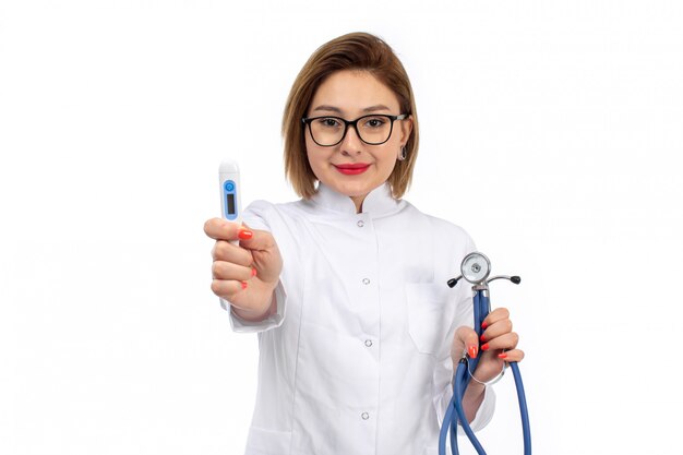 A front view young female doctor in white medical suit with stethoscope smiling on the white