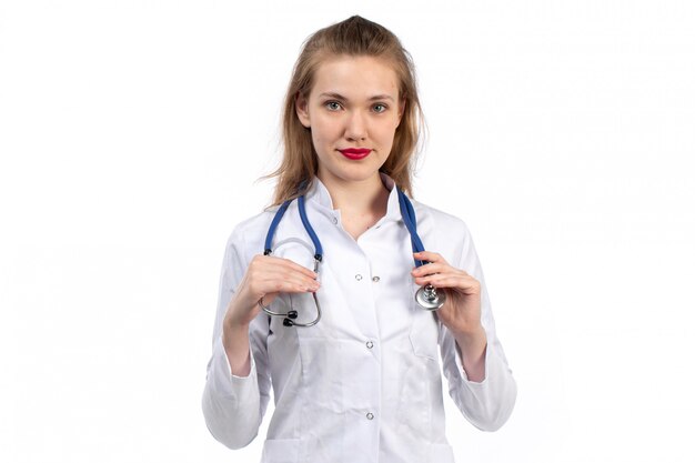 Вид спереди молодая женщина-врач в белом медицинском костюме с стетоскоп, улыбаясь на белом