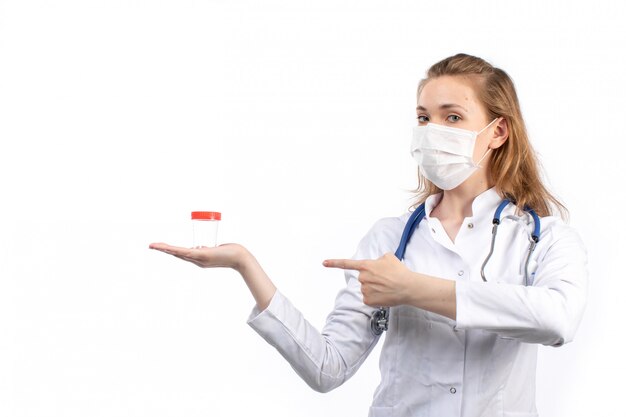 청진 기 흰색 보호 마스크 포즈 지주 플라스 크를 입고 흰색 의료 소송에서 전면보기 젊은 여성 의사