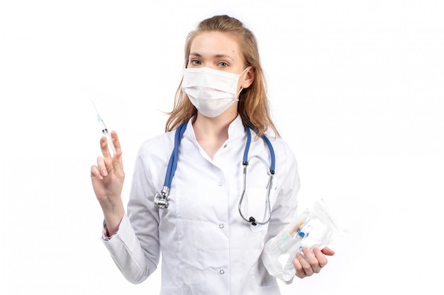 청진 기 흰색 보호 마스크를 입고 흰색에 주사를 입고 흰색 의료 소송에서 전면보기 젊은 여성 의사