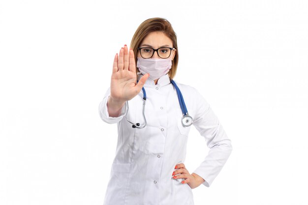 白に一時停止の標識を示す白い防護マスクを身に着けている聴診器で白い医療訴訟で正面若い女医