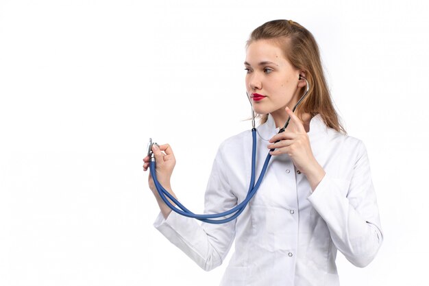 Вид спереди молодая женщина-врач в белом медицинском костюме со стетоскопом на белом