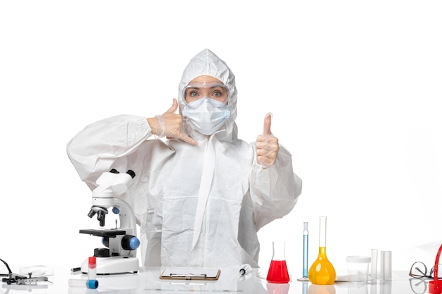 Front view young female doctor in white protective suit with mask due to covid posing on white background virus pandemic splash covid-