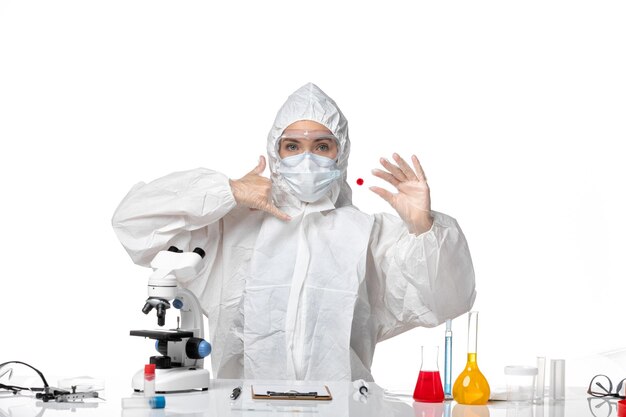 Front view young female doctor in white protective suit with mask due to covid on the white background pandemic covid- virus health