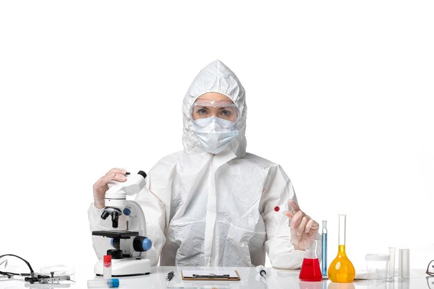 Front view young female doctor in white protective suit with mask due to covid on white desk pandemic covid- virus health