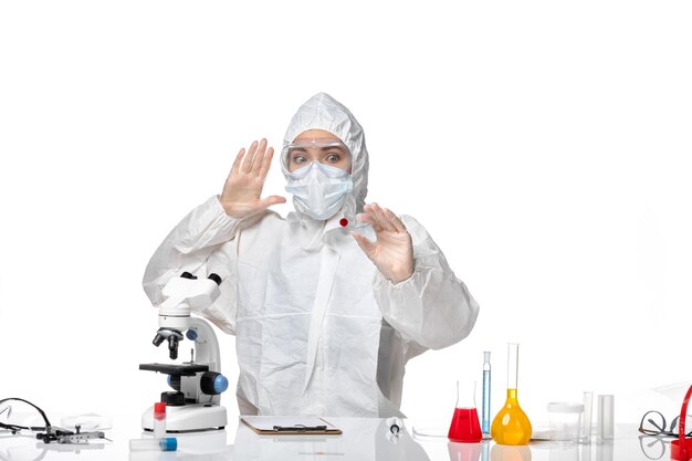 Вид спереди молодая женщина-врач в белом защитном костюме с маской из-за covid, работающего на белом фоне, пандемический всплеск вируса, здоровье covid