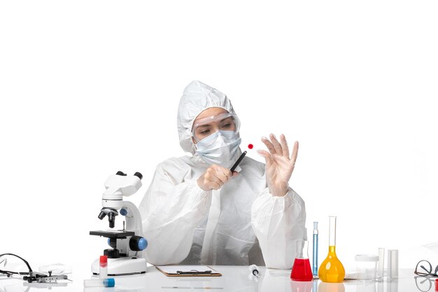 Вид спереди молодая женщина-врач в белом защитном костюме с маской из-за covid, работающего на белом фоне, пандемического вируса, здоровья covid
