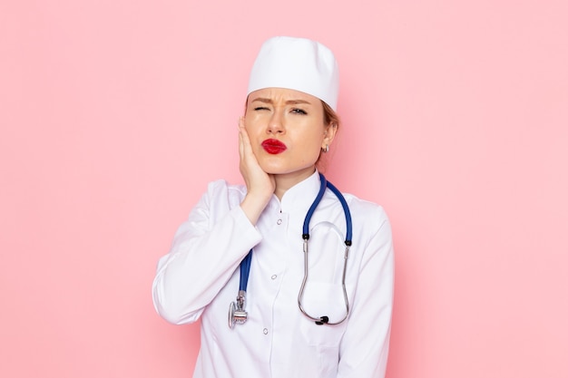 파란색 청진 기 핑크 공간 작업 여자 여자 감정에 포즈와 흰색 정장에 전면보기 젊은 여성 의사