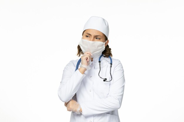 흰색 표면에 코로나 바이러스 깊은 사고로 인해 멸균 마스크와 장갑 전면보기 젊은 여성 의사