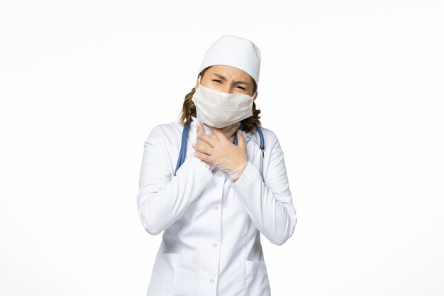 Вид спереди молодая женщина-врач со стерильной маской и перчатками из-за коронавируса на светлой белой поверхности