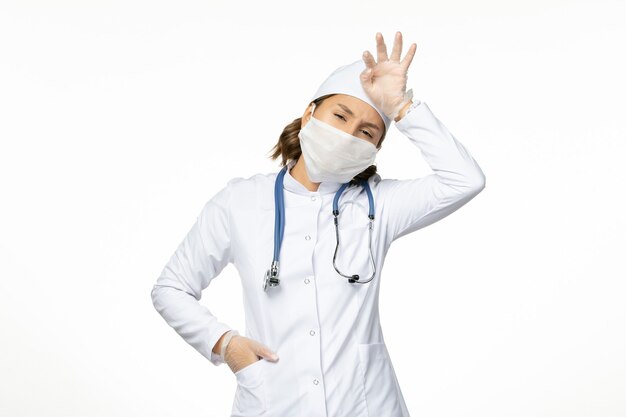白い表面にコロナウイルスによる滅菌マスクと保護手袋を着用した正面図若い女性医師