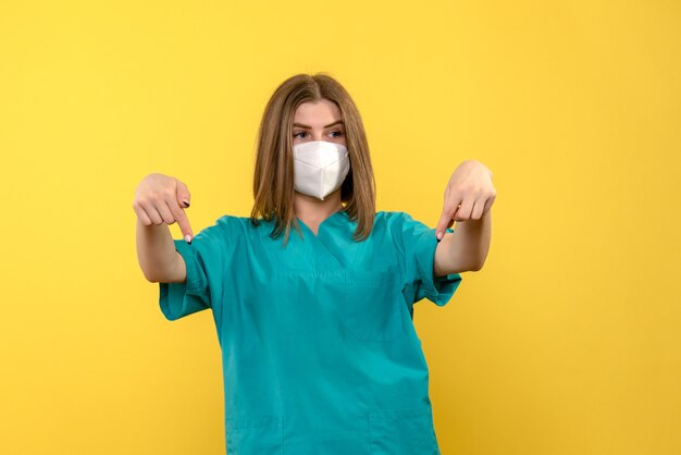 Front view of young female doctor on yellow wall