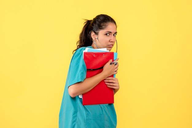 Front view of young female doctor on yellow wall