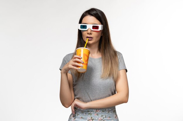 Вид спереди молодая женщина, пьющая соду в солнцезащитных очках d на светлой белой поверхности