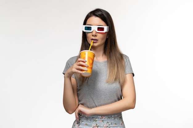 Вид спереди молодая женщина, пьющая соду в солнцезащитных очках d на светлой белой поверхности