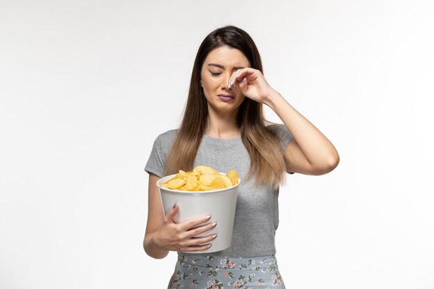 Front view young female eating cips and watching movie on the white surface