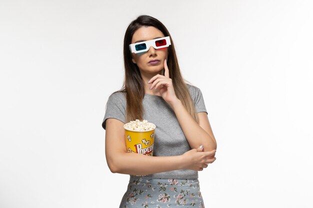 Front view young female eating popcorn and watching movie in d sunglasses on white desk