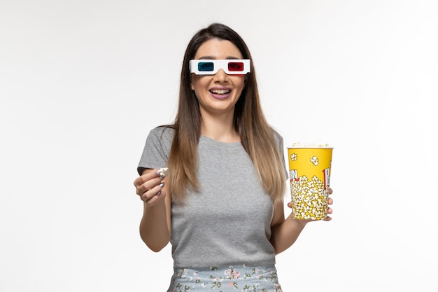 Front view young female eating popcorn and watching movie in d sunglasses on the white surface