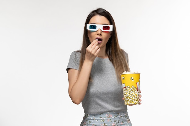 Front view young female eating popcorn and watching movie in d sunglasses on white surface