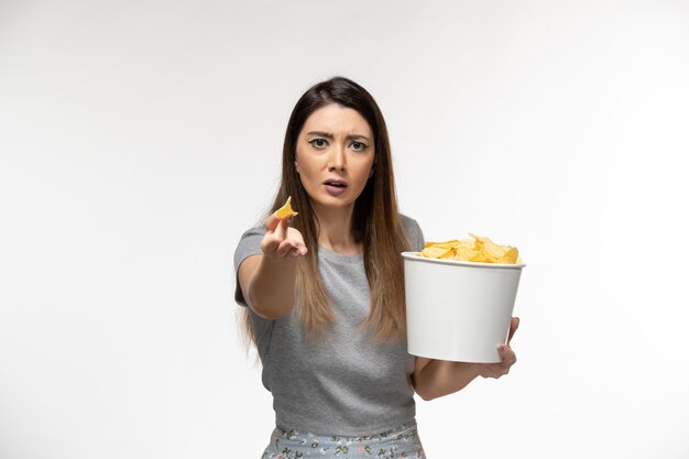 Front view young female eating potato chips watching movie on light white surface