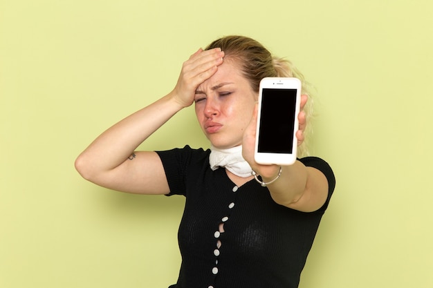 Front view young female feeling very ill and sick holding her phone on the green desk sickness medicine illness