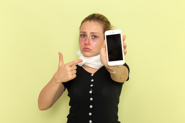 Free photo front view young female feeling very ill and sick holding her phone on the green wall sickness medicine illness