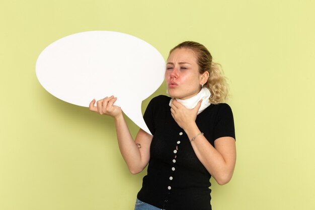 Front view young female feeling very ill and sick holding huge white sign holding her throat on green wall sickness medicine health illness