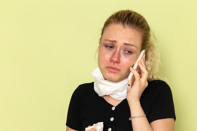 Front view young female feeling very ill and sick talking on the phone on the green desk sickness medicine illness girl