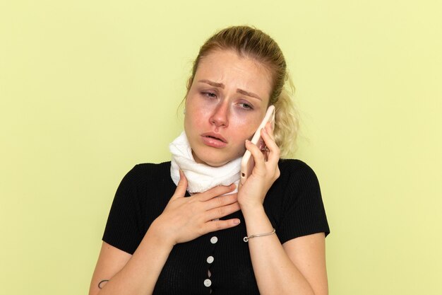 Front view young female feeling very ill and sick talking on the phone on the green wall sickness medicine illness