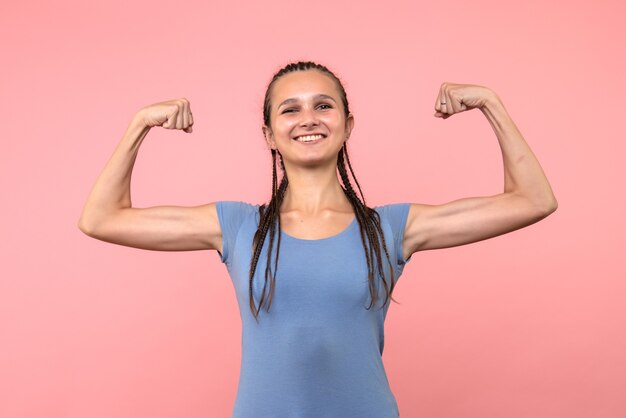 Front view of young female flexing on pink