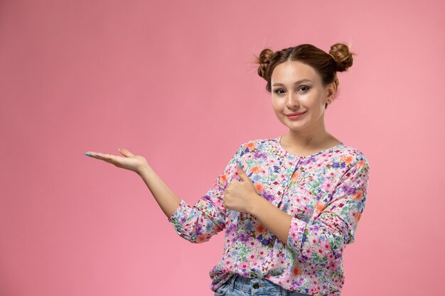 Vista frontale giovane femmina in camicia fiore progettato e blue jeans in posa con un leggero sorriso su sfondo chiaro