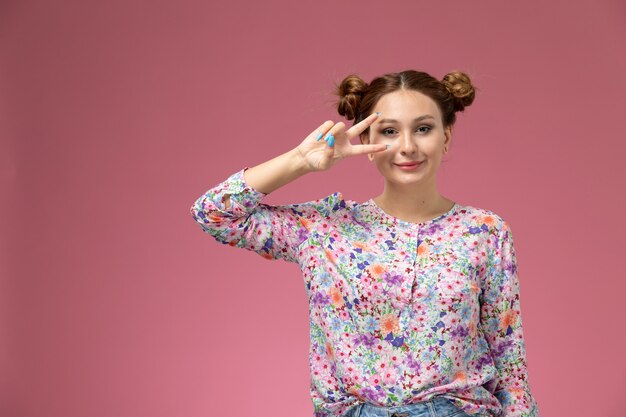 花の正面の若い女性のデザインのシャツとブルージーンズ、ピンクの背景にかわいい表情で笑顔