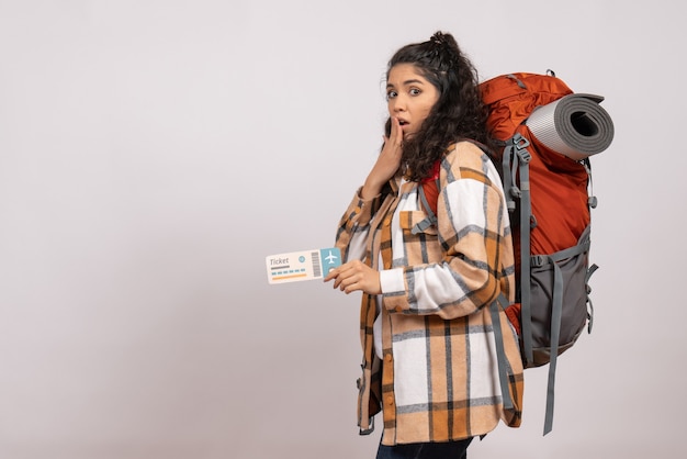 Бесплатное фото Вид спереди молодая женщина, идущая в походы с билетом на белом фоне, поездка, воздушный туристический лес, отдых, полет в кампусе