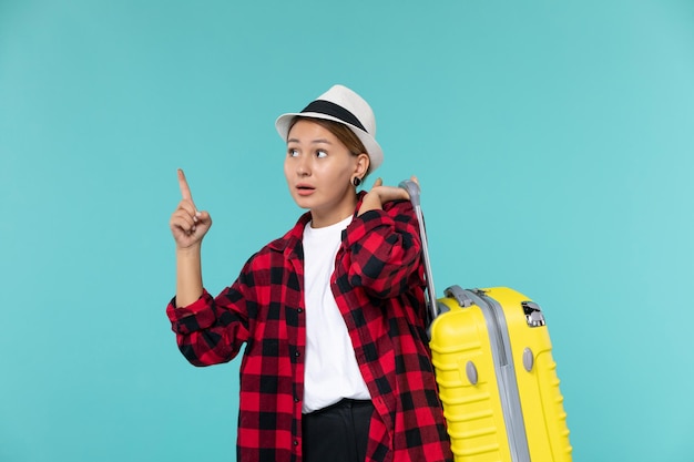 Вид спереди молодая женщина, отправляющаяся в отпуск со своей желтой сумкой на синем пространстве