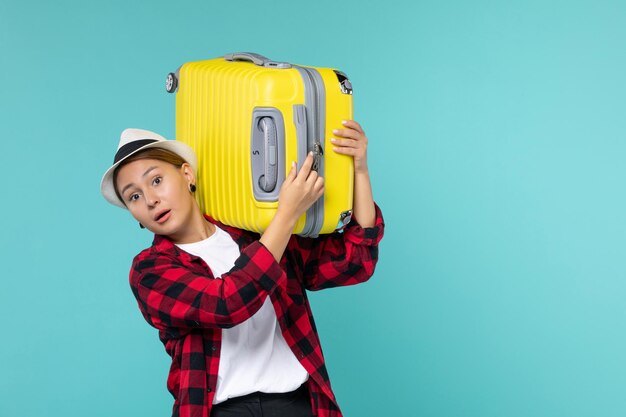 Front view young female going in vacation with her yellow bag on a light-blue space