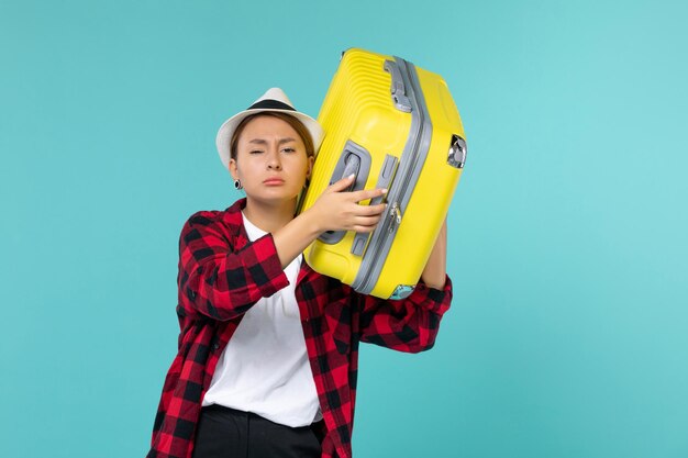 Front view young female going in vacation with her yellow bag on the light blue space