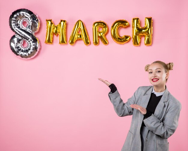 Free photo front view young female in gray suit with march decoration on pink background equality holiday horizontal womens day party woman sensual present color