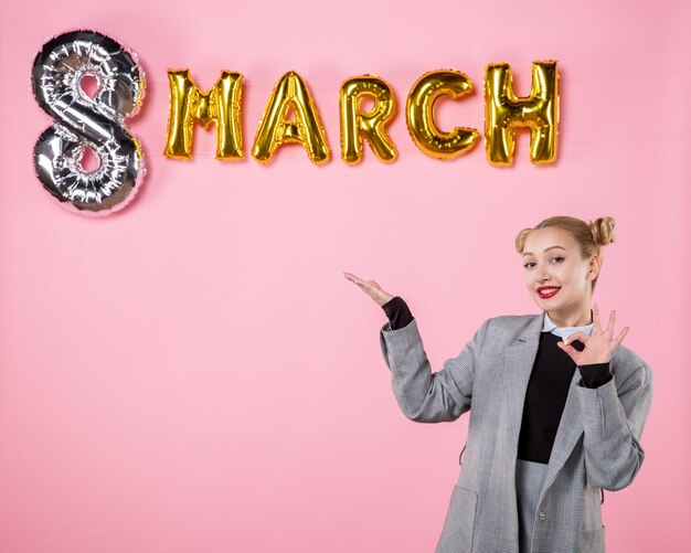 Free photo front view young female in gray suit with march decoration on pink background equality holiday horizontal womens day woman sensual present colors party