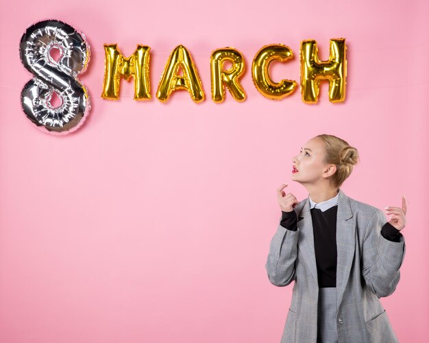 Front view young female in gray suit with march decoration on pink background equality holiday womens day party woman sensual present color