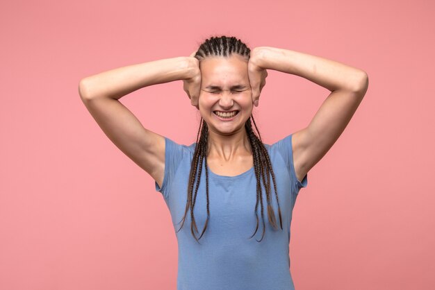 Front view of young female having headache on pink