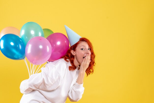 Front view young female hiding colorful balloons behind her back new year emotion party xmas woman