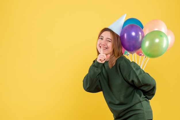 Vista frontale giovane femmina nascondendo palloncini colorati