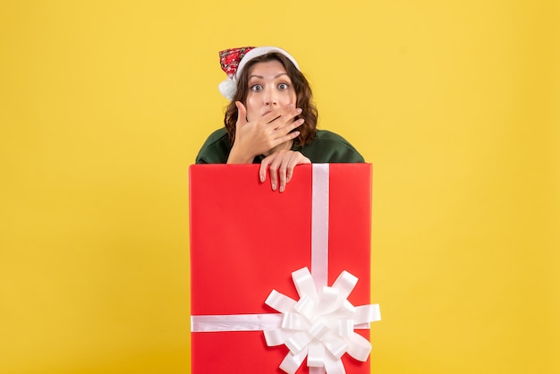 Free photo front view young female hiding inside box with surprised face on yellow