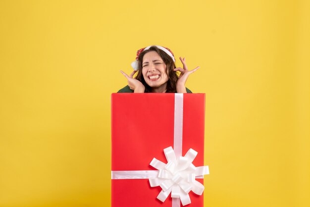 Free photo front view young female hiding inside present box on yellow