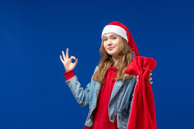 Front view young female holding bag with presents on a blue background christmas holiday emotion