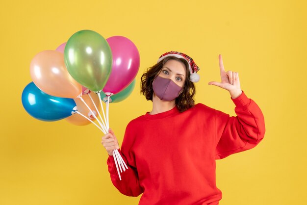 Front view young female holding balloons in sterile mask on yellow 