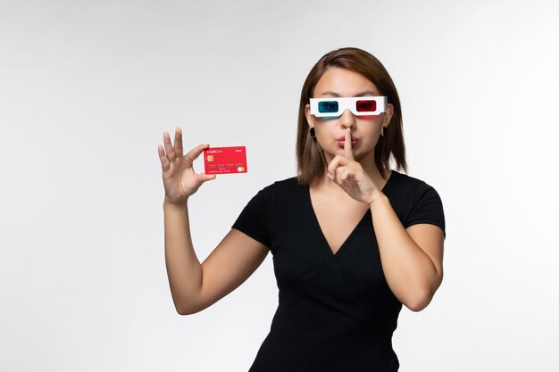 Front view young female holding bank card in -d sunglasses on light-white surface